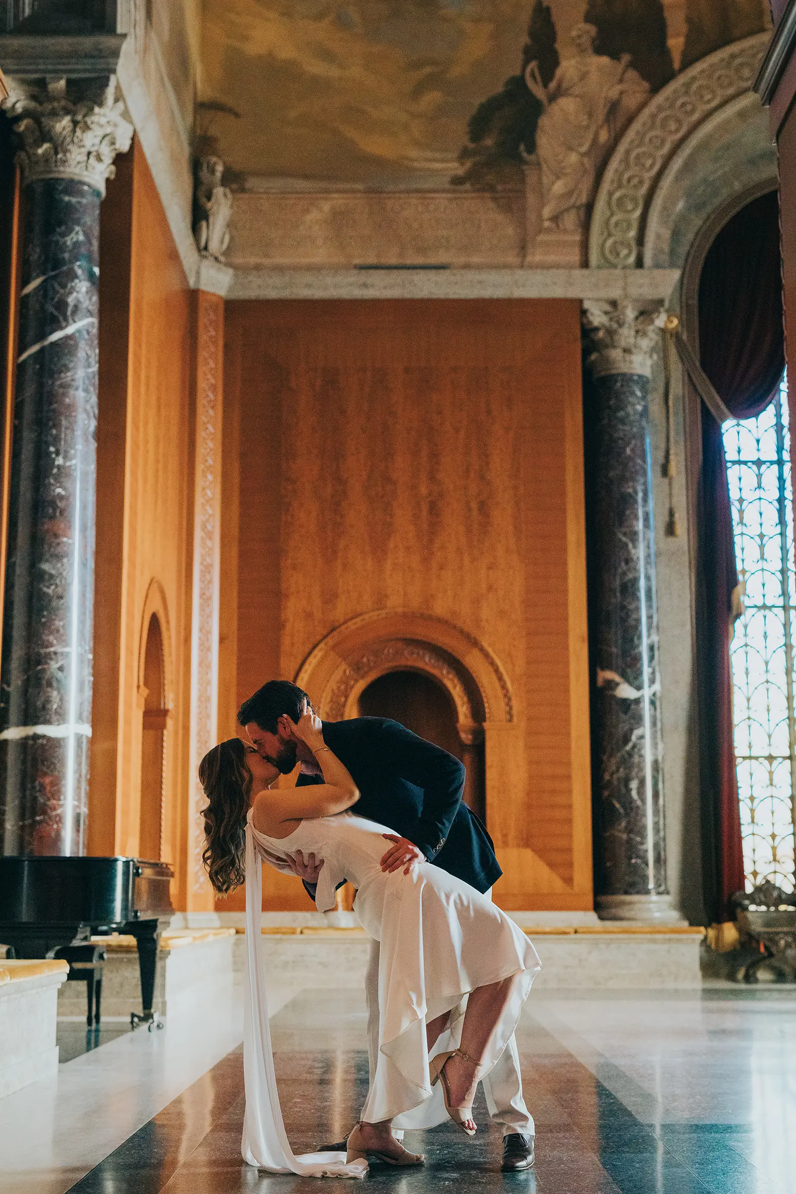 Romantic dip kiss inside the Armstrong Browning Library in Waco Texas surrounded by marble floors and warm golden light.