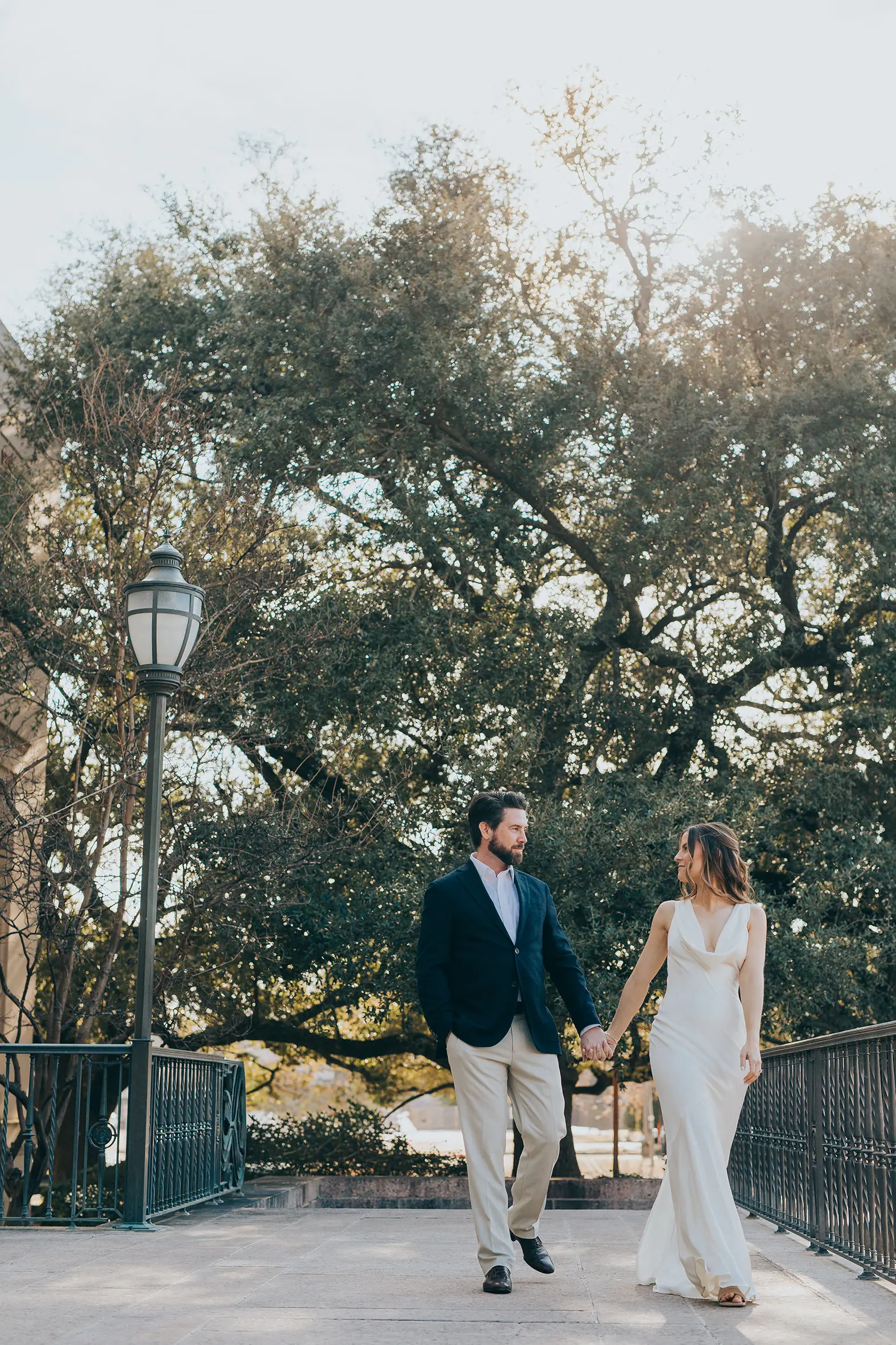 Natalie and Spencer walking hand in hand across the bridge near Baylor University during their Waco Texas engagement session.