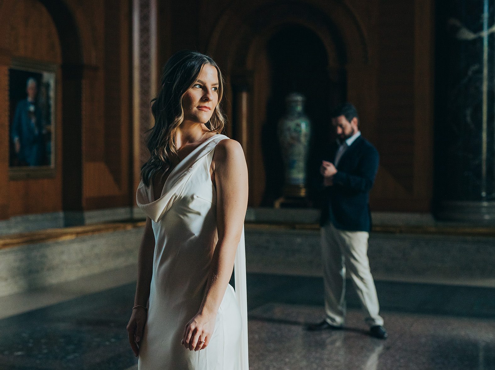 Couple standing separately on marble floors inside the Armstrong Browning Library in Waco during their engagement session.